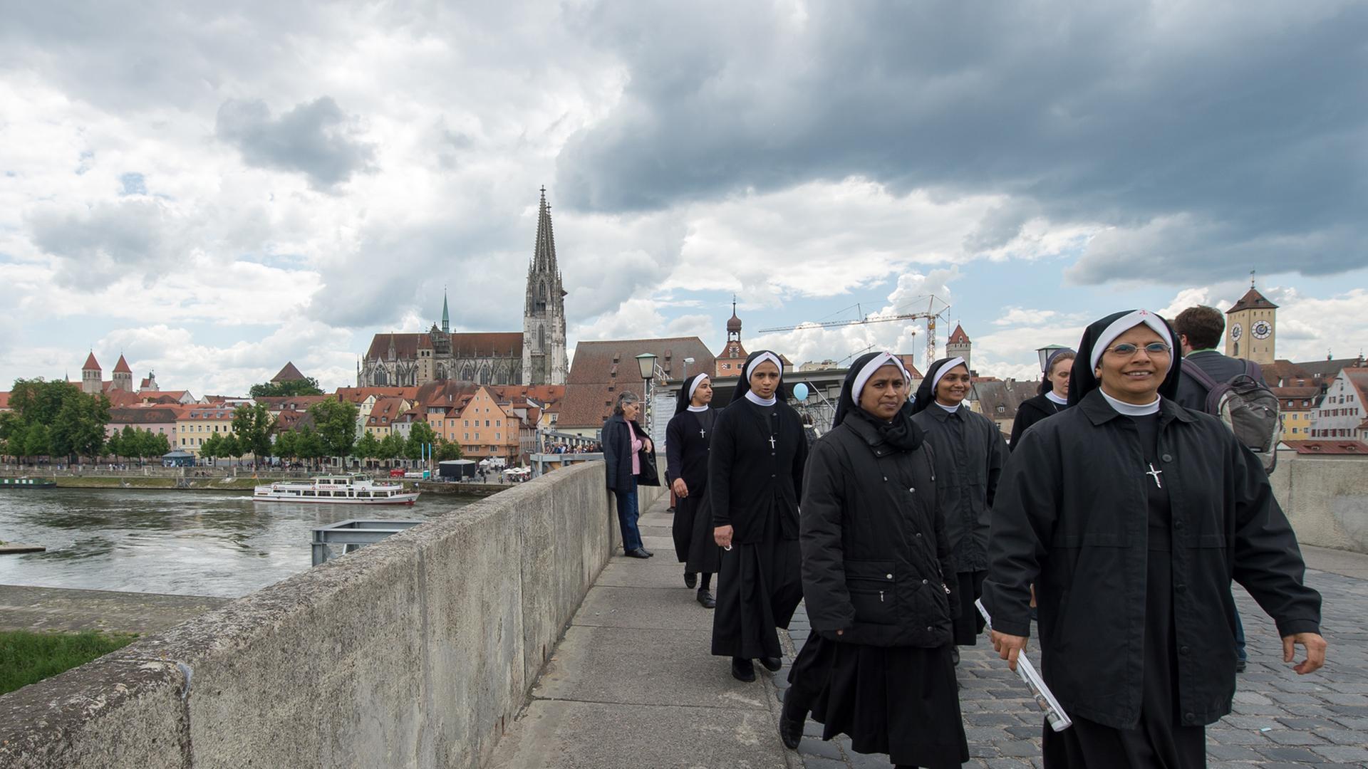 Ordensschwestern gehen am 31. Mai 2014 während des Katholikentags in Regensburg auf der Steinernen Brücke.