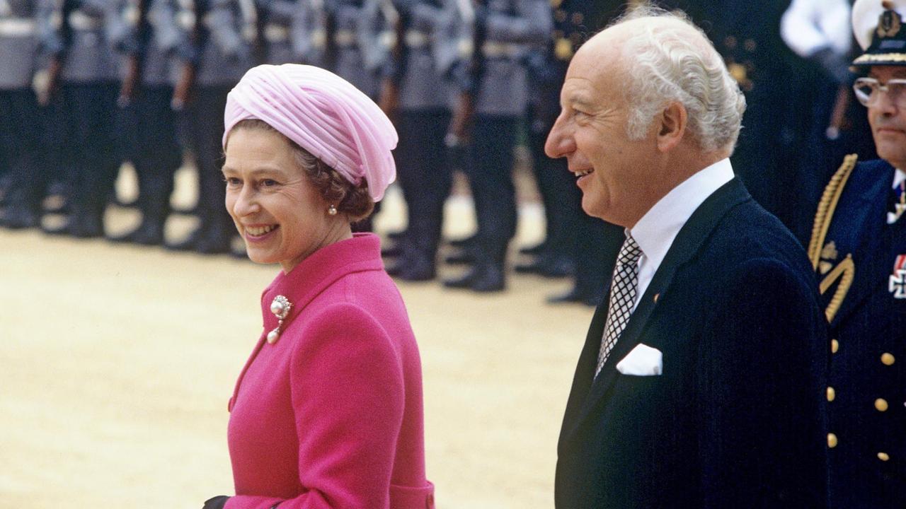 Eine Königin und ein Mann in besten Jahren von der Seite schreiten eine Ehrenformation ab.