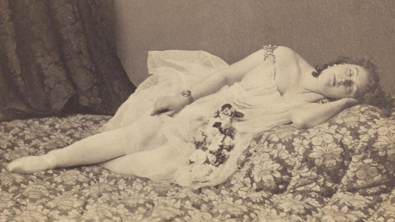 Eine Frau liegt auf einem Bett. Schwarzweißfoto.