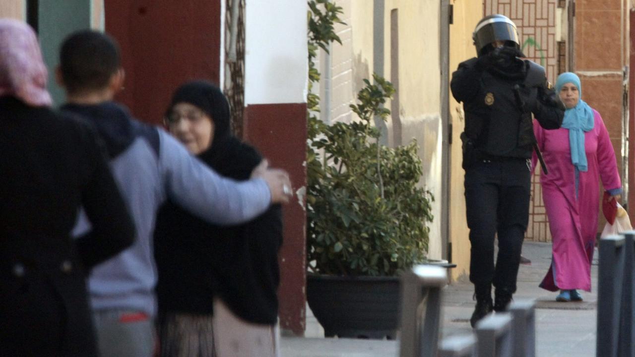 Ein Polizist läuft zwischen muslimischen Bewohnern nachdem die Polizei vier mutmaßliche Dschihadisten in El Principe, einem Randgebiet von Ceuta, am 24.01.2015 festgenommen hatte.