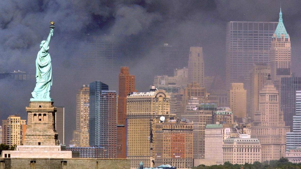 Blick auf die Freiheitsstatue vor schwarzem Rauch, der nach dem Anschlag auf das World Trade Center am 11.9.2001 in New York aus den Trümmern der eingestürzten Zwillingstürme aufsteigt.
