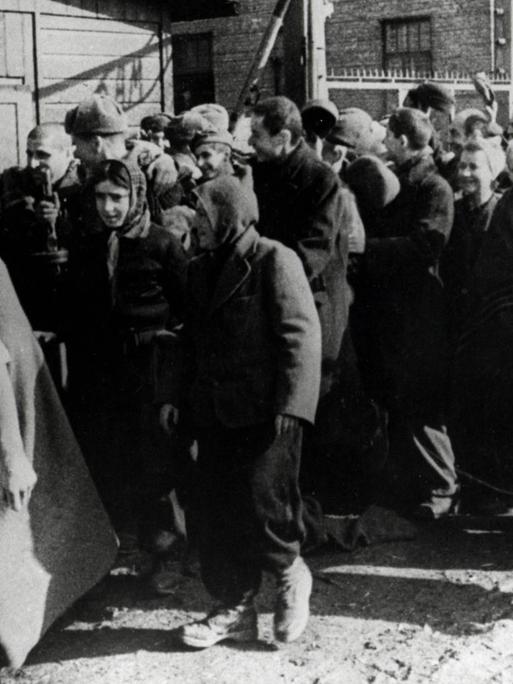 Überlebende des Konzentrationslagers Auschwitz verlassen das Lager und machen dabei Siegesgesten.