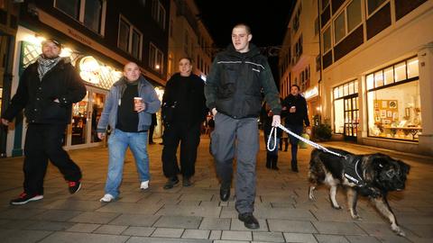 Sympathisanten einer Düsseldorfer Bürgerwehr ziehen im Dunkeln mit einem Hund durch die Altstadt.