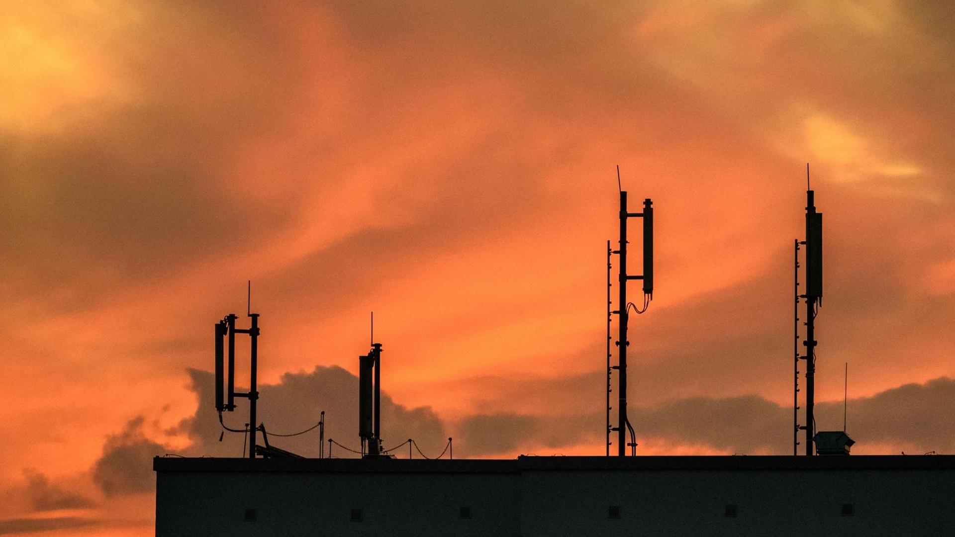 Mobilfunk-Antennen auf einem Dach während des Sonnenuntergangs