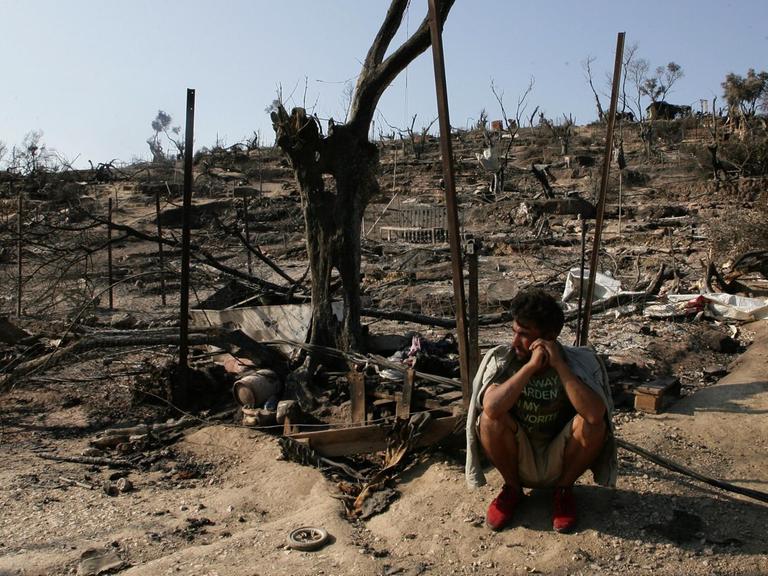 Ein Flüchtling sitzt vor den Überresten des abgebrannten Flüchtlingslagers Moria, auf der griechischen Insel Lesbos.