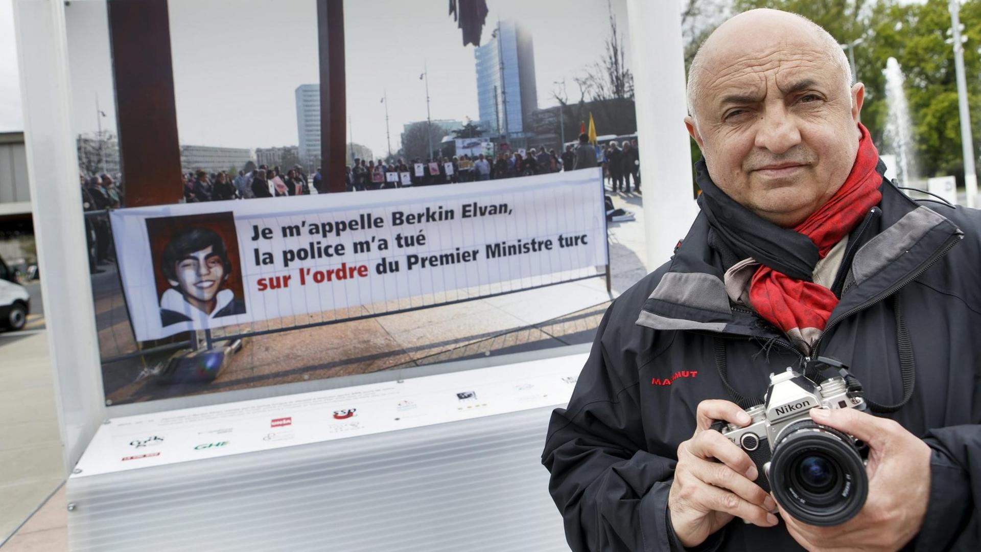 Im Vordergrund rechts sieht man den Genfer Fotografen Demir Sönmez mit einer Kamera in der Hand. Im Hintergrund sein Foto einer Demonstration auf dem Genfer Place de la Nation im März 2014. Auf der Aufnahme ist ein Transparent zu sehen, auf dem die Demonstranten den türkischen Präsidenten Erdogan persönlich für den Tod des 15-jährigen Berkin Elvan verantwortlich machen.