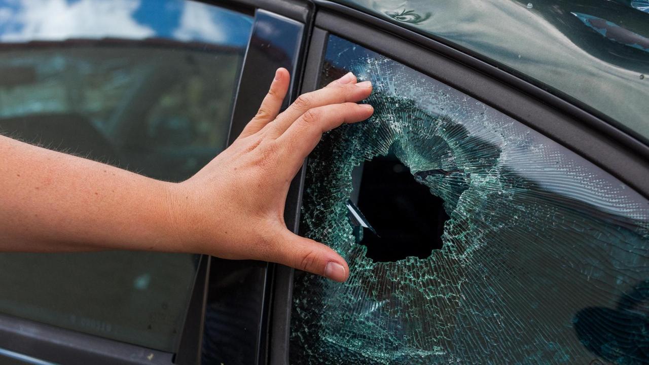 Ein Anwohner zeigt den Schaden an einem Autofenster, den ein Hagelsturm hinterlassen hat.