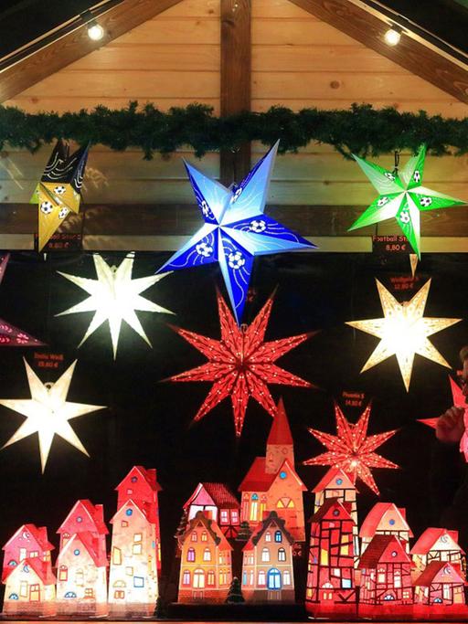 Das Bild zeigt beleuchtete Papiersterne und Papierhäuser auf dem Weihnachtsmarkt in Magdeburg (Sachsen-Anhalt).