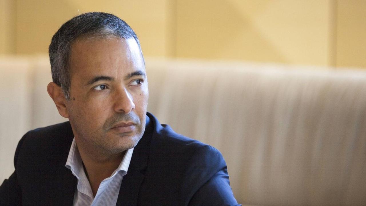 Kamel Daoud sitzt im Anzug vor edlem Ambiente.