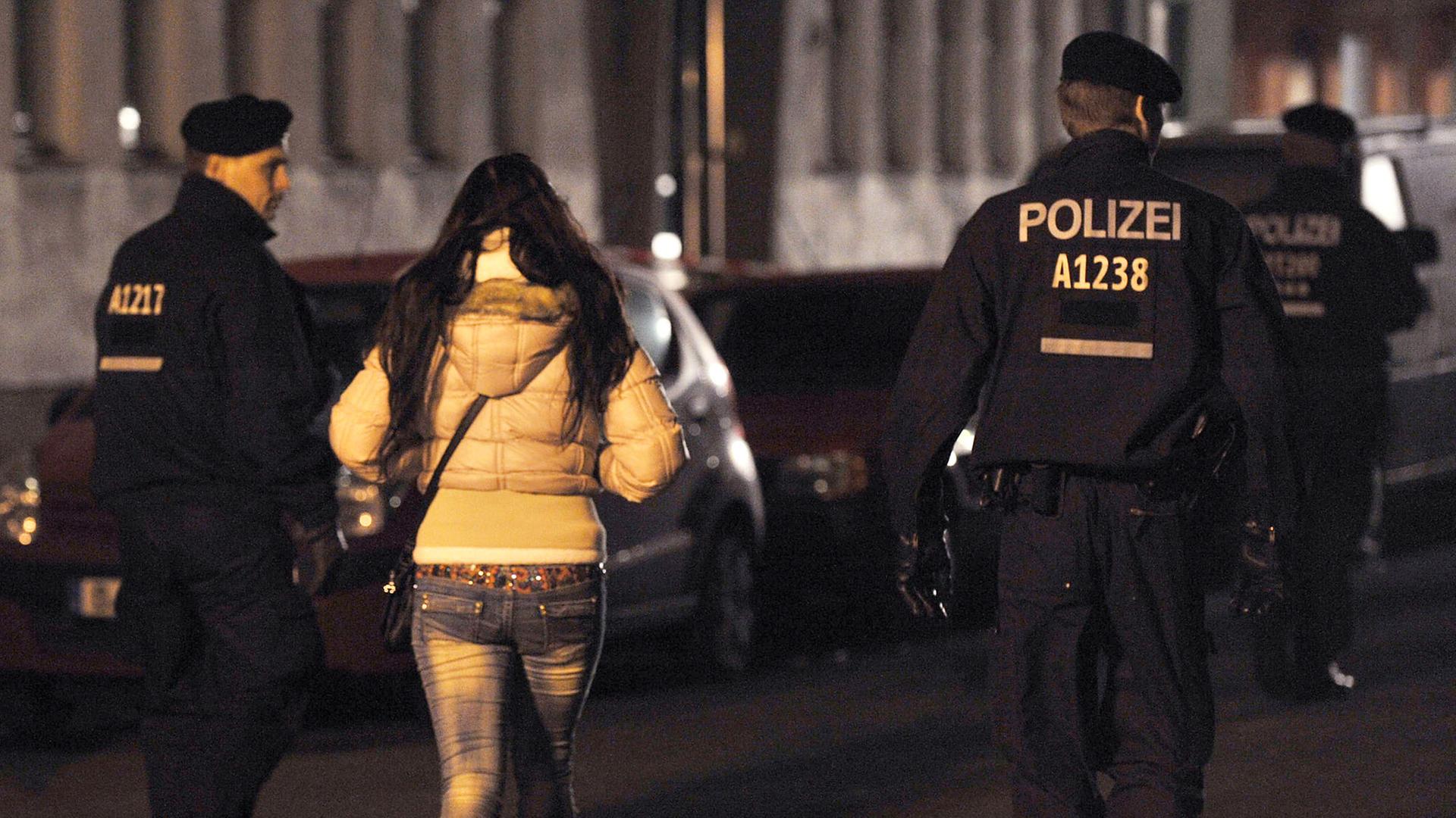 Polizisten begleiten bei einem Polizeieinsatz mit Durchsuchungen am 08.11.2013 in der Kurfürstenstraße in Berlin eine Frau zu einem Kontrollpunkt.