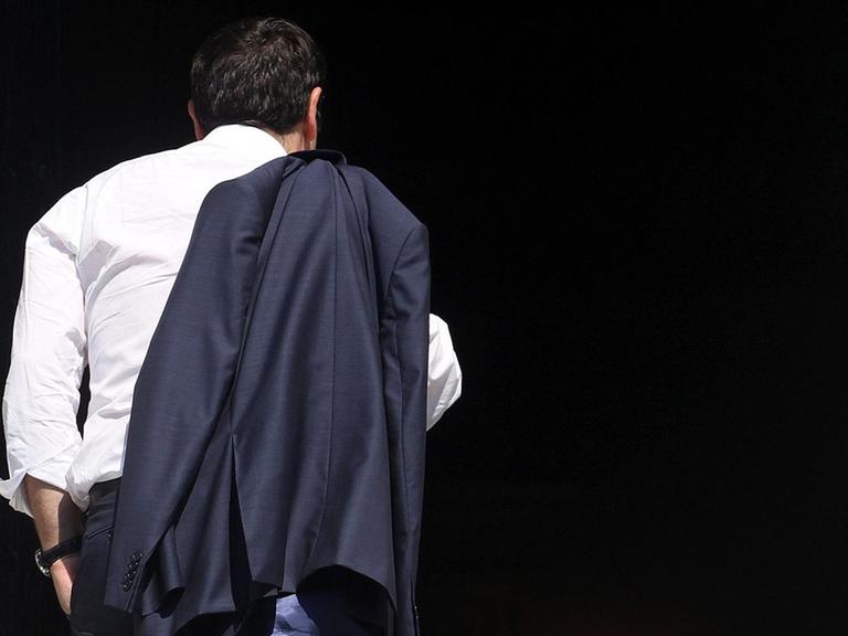 Alexis Tsipras kehrt in Athen in sein Büro zurück. Man sieht ihn von hinten, seine Jacke hängt über der Schulter.