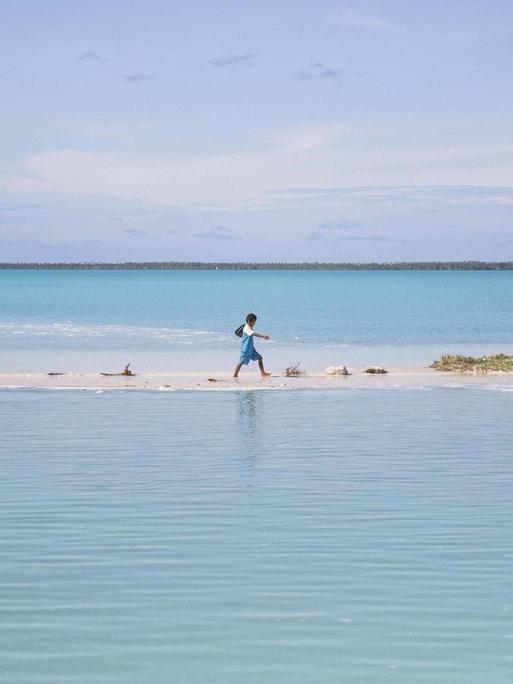 Ein Junge watet auf einer Insel des Pazifikstaates Kiribati durch eine Lagune.