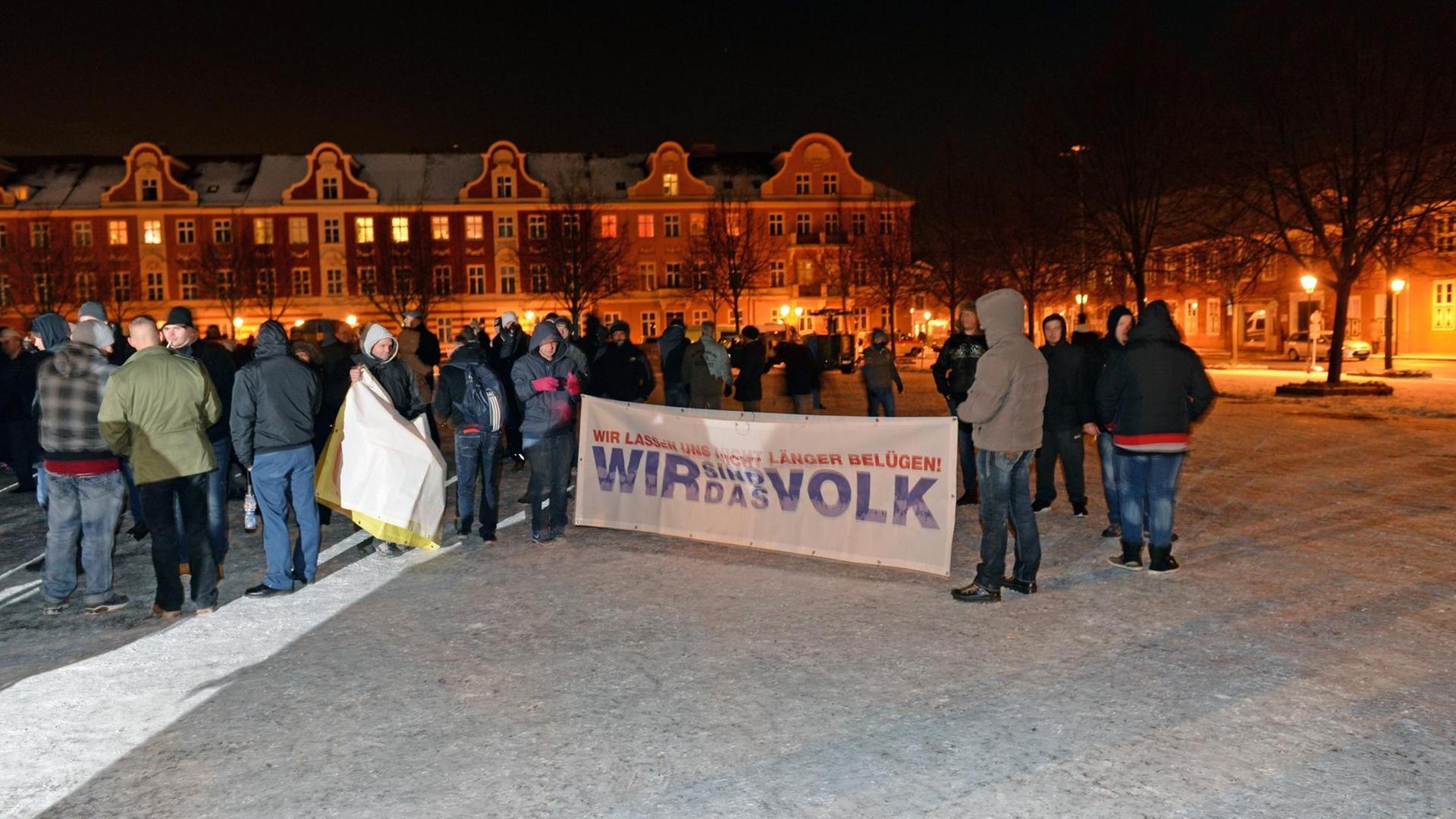 Pogida-Demonstranten stehen am 20.01.2016 auf dem Bassinplatz in Potsdam (Brandenburg) mit einem Transparent "Wir lassen uns nicht länger belügen! Wir sind das Volk".