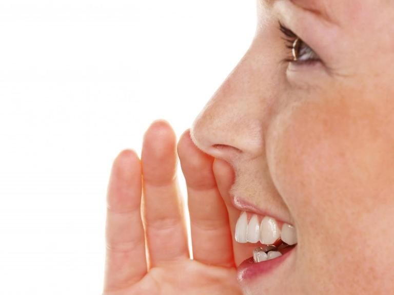 Eine junge Frau spricht und hält dabei die Hand an das Gesicht.