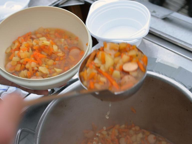 Gerolf Wortmann, Ehrenamtlicher Helfer der Caritas, füllt am 19.11.2013 vor dem Bahnhof in Bremen Suppe in einen Teller.