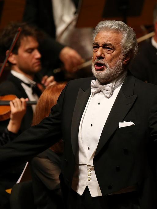 Placido Domingo steht bei einer Nabucco Aufführung vor dem Orchester und singt.