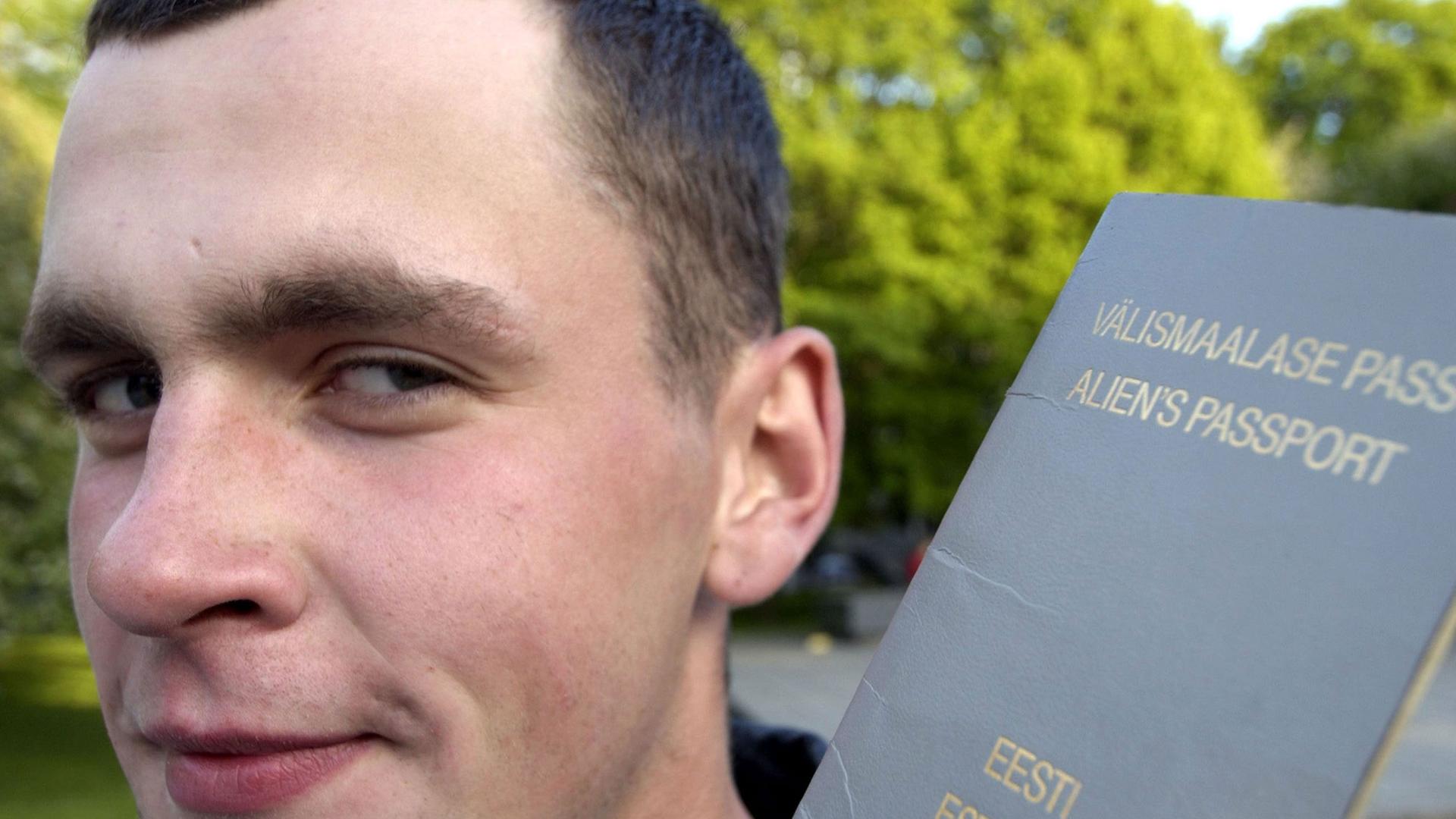 Ein junger Russe hält in Tallinn seine estnischen Pass in der Hand.