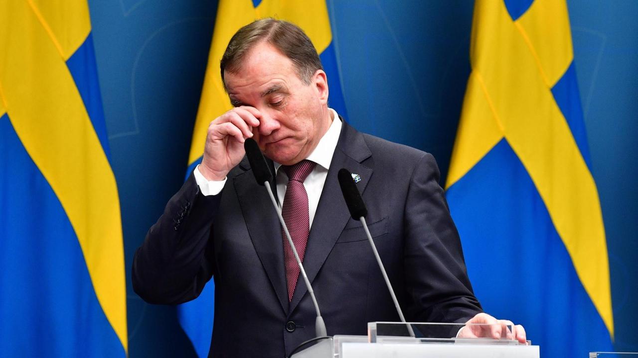 Premierminister Stefan Löfven steht vor einer schwedischen Flagge am Rednerpult.