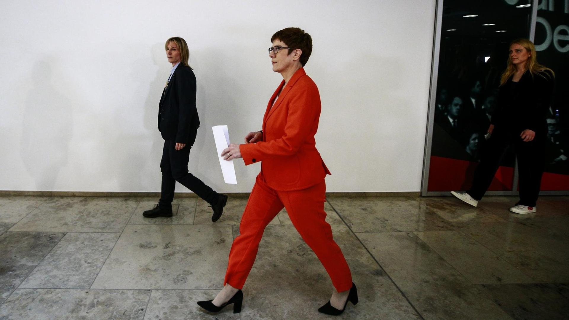 CDU-Chefin und Verteidigungsministerin Annegret Kramp-Karrenbauer läuft in einem Gebäude einen Flur entlang. Sie trägt einen roten Hosenanzug.