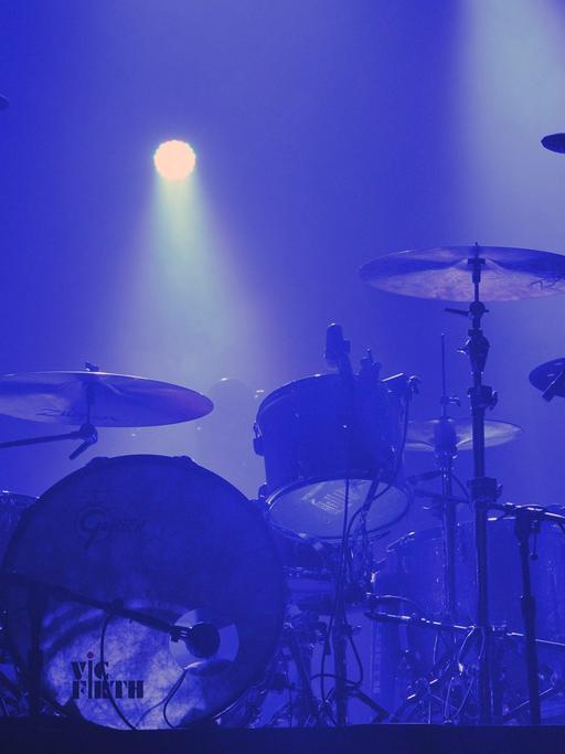 Ein Schlagzeug steht auf einer blau beleuchteten Bühne.
