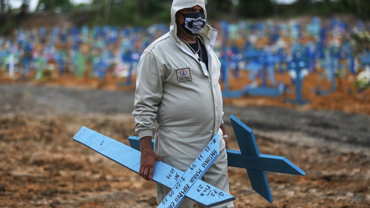 Ein Friedhofsmitarbeiter in Manaus, Brasilien, mit Kreuzen für neue Gräber.