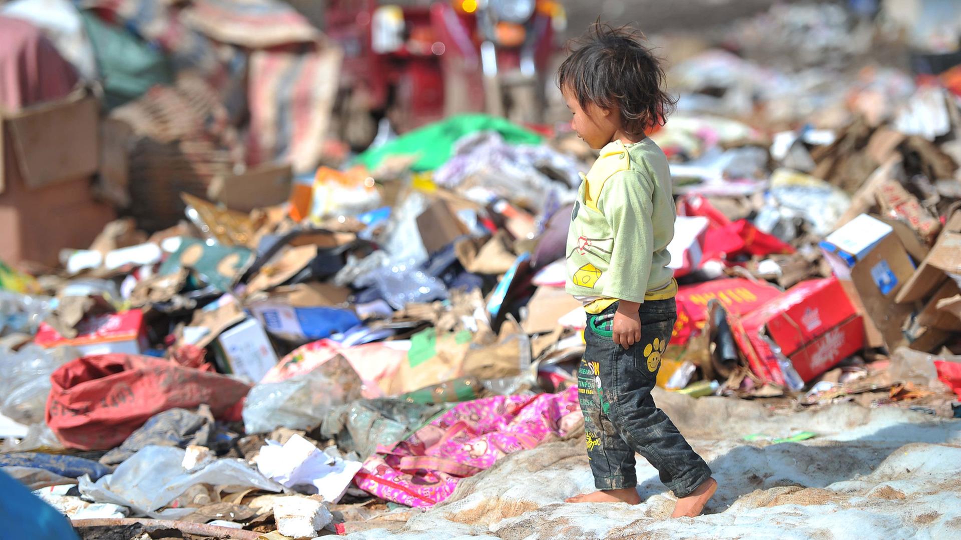 Ein kleiner Junge läuft über eine Müllkippe