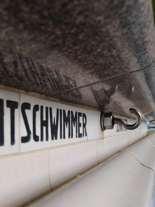 Blick auf ein leeres Schwimmbadbecken. Auf der linken Seite des Bildes dominiert der Schriftzug "Nichtschwimmer" am Beckenrand.
