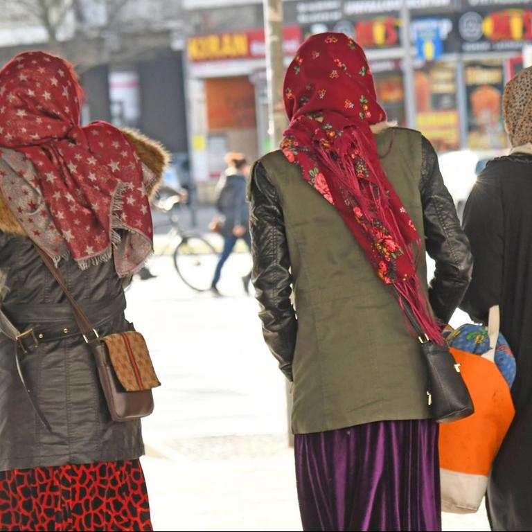 Muslimas mit bunten Kopftuch stehen an der Strasse am Kottbusser Tor in Berlin.