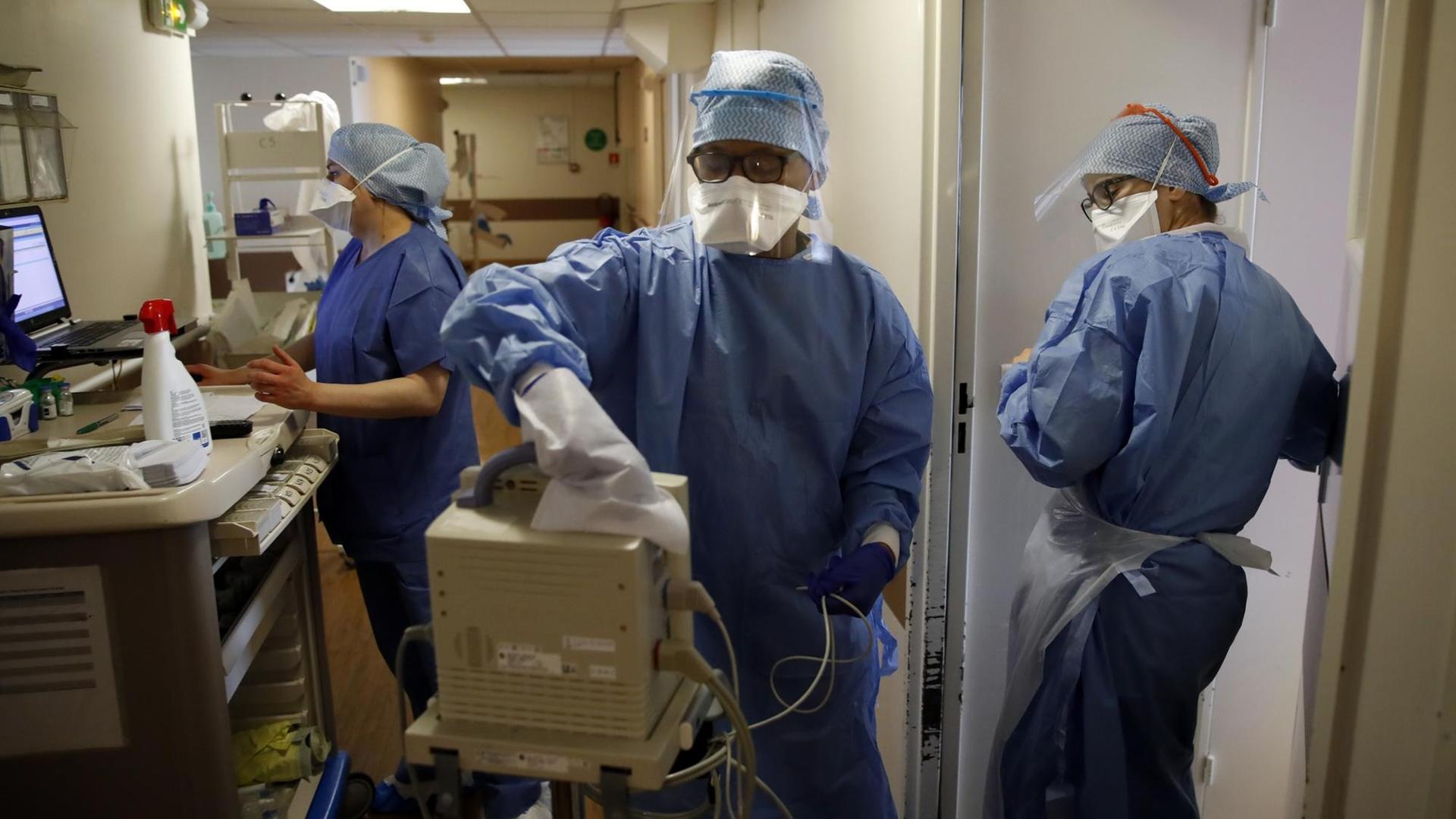 Medizinisches Personal in Schutzkleidung in einem Krankenhaus in Paris, in dem Covid-19-Patienten behandelt werden. Eine Person desinfiziert ein technisches Gerät.