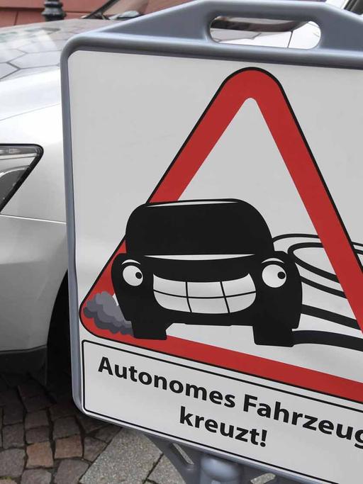 Vor dem Forschungsfahrzeug _Cocar_ für autonomes Fahren des Forschungszentrum Informatik (FZI) in Karlsruhe (Baden-Württemberg) steht am 28.04.2016 ein Schild, auf dem _Autonomes Fahrzeug kreuzt" zu lesen ist.