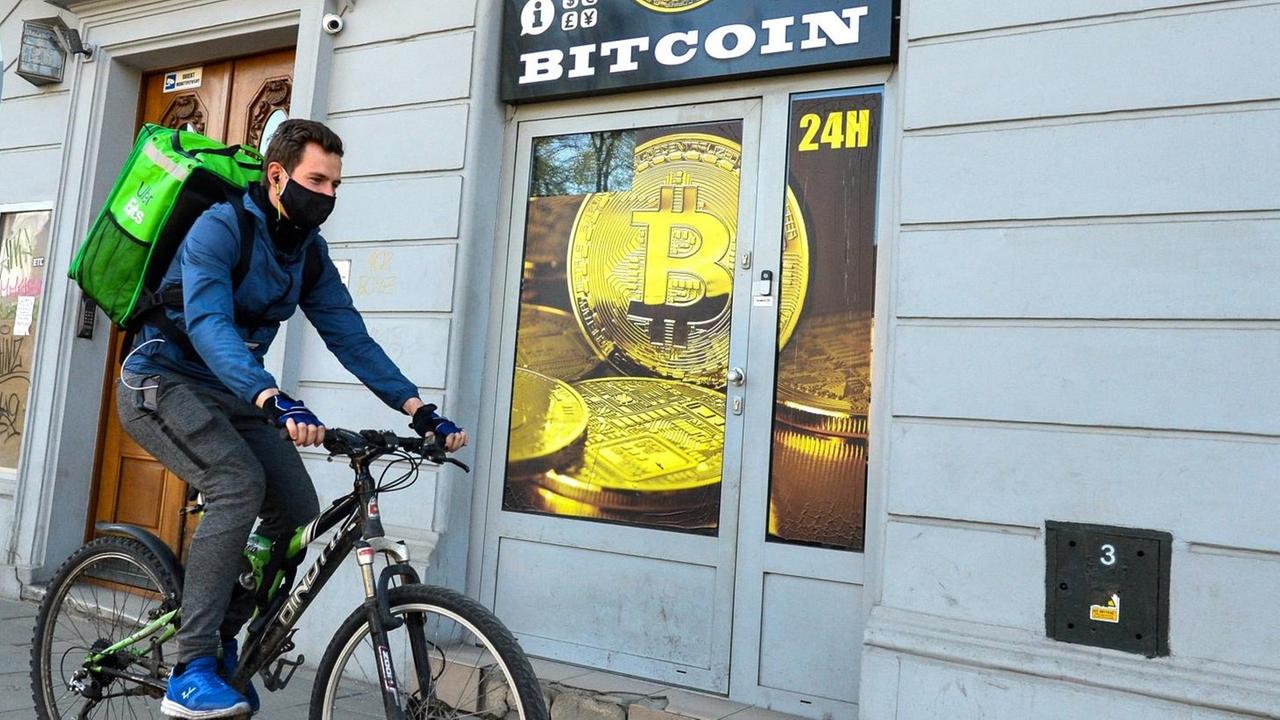 Ein Radfahrer mit Mundschutz fährt an einem Bitcoin-Wechsel-Laden in Krakau vorbei.