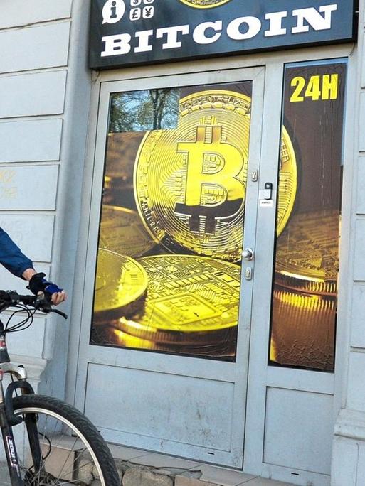 Ein Radfahrer mit Mundschutz fährt an einem Bitcoin-Wechsel-Laden in Krakau vorbei.