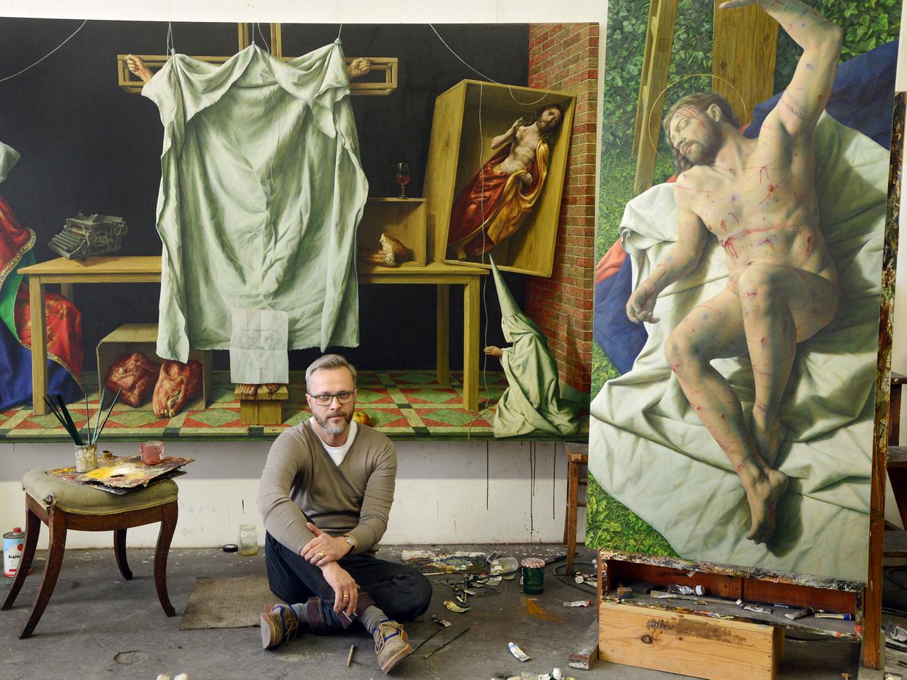 Der Leipziger Maler Michael Triegel, der auch als Papstmaler bekannt ist, vor seinem Bild "Kreuzabnahme" (r), das in einer Ausstellung anlässlich des Deutschen Katholikentages im Museum Obermünster in Regensburg gezeigt wird.