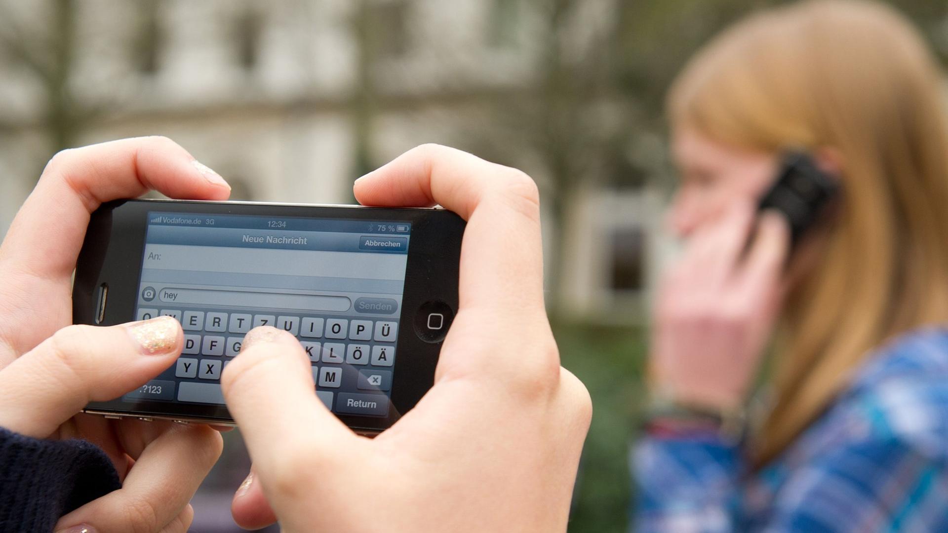 Schüler schreiben SMS und telefonieren auf einem Schulhof in Braunschweig