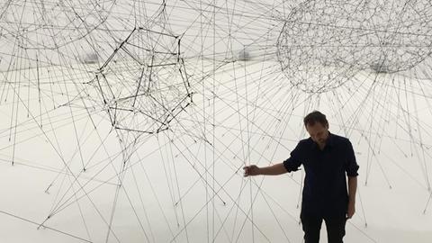 Tomás Saraceno inmitten seiner spinnwebenartigen Installation "On Air" im Palais de Tokyo in Paris.