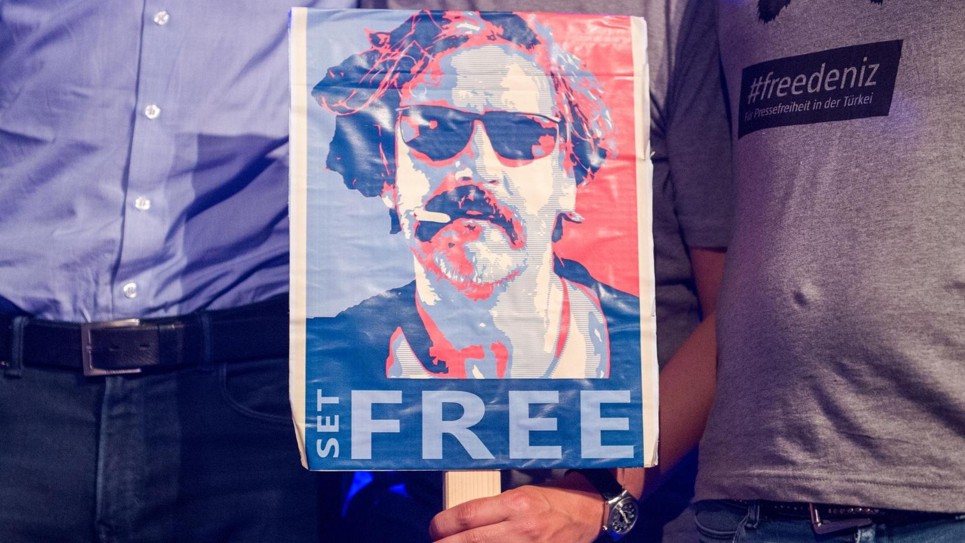 Das Archivbild zeigt ein Schild mit der Aufschrift "Free" und einem Foto des inhaftierten Journalisten Deniz Yücel.