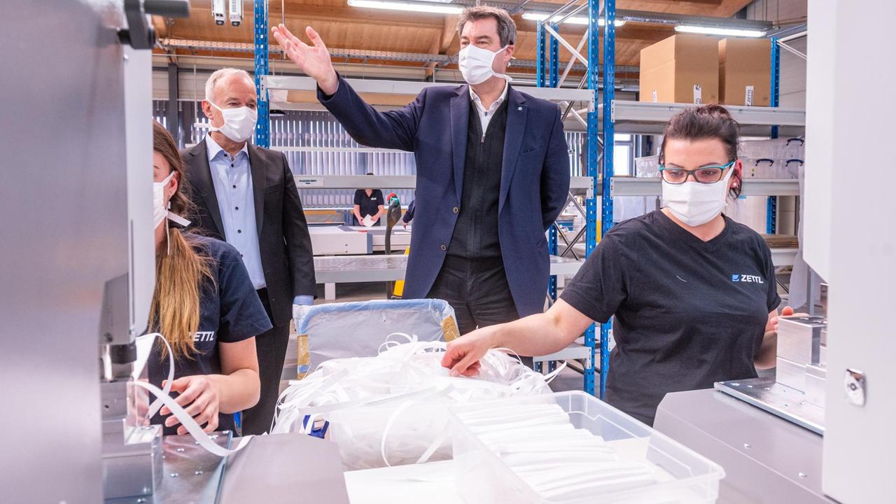 Markus Söder (CSU) steht mit einer Mundschutzmaske in einer Produktionshalle des Automobilzulieferers Zettl. Das Unternehmen hat angesichts der Corona-Krise seinen Betrieb auf die Produktion von Schutzmasken umgestellt.