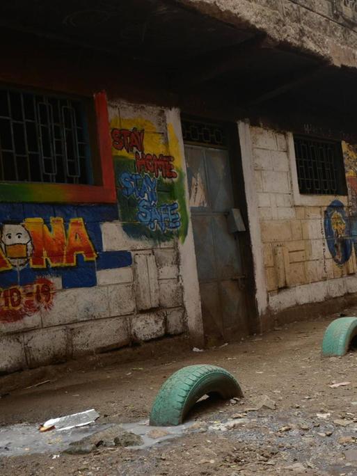 In der kenianischen Hauptstadt Nairobi läuft eine Frau an einem bunten Graffito mit Corona-Verhaltensregeln auf einer Hauswand vorbei.