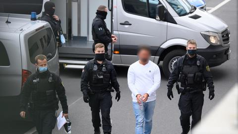 Ein verdächtiger Mann im Fall des Kunstdiebstahls im Grünen Gewölbe wird von Polizisten in das Gebäude des Oberlandesgerichts geführt. Knapp ein Jahr nach dem Kunstraub im Dresdner Grünen Gewölbe hat die Polizei am Morgen in Berlin drei Tatverdächtige festgenommen.
