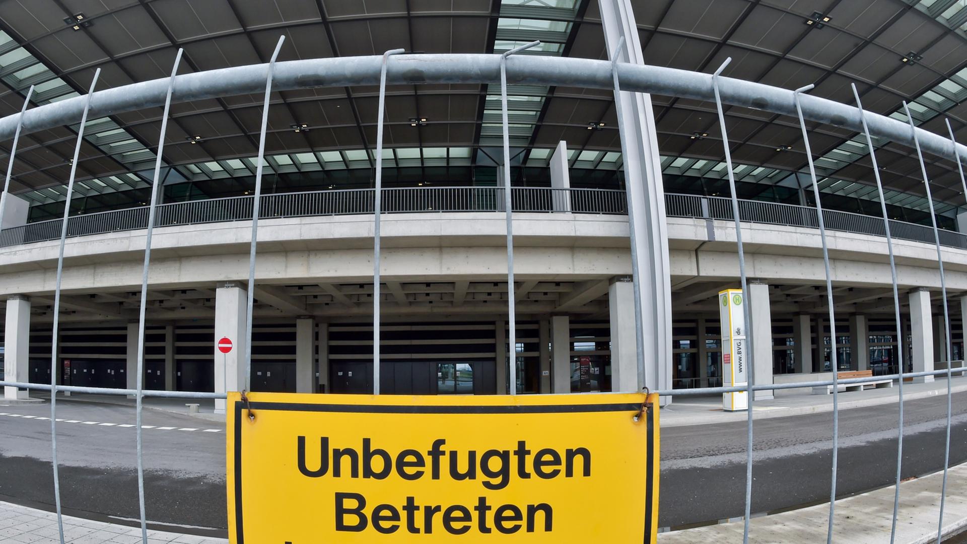 Ein Bauzaun mit einem Schild "Unbefugten Betreten der Baustelle verboten", dahinter das Terminalgebäude.