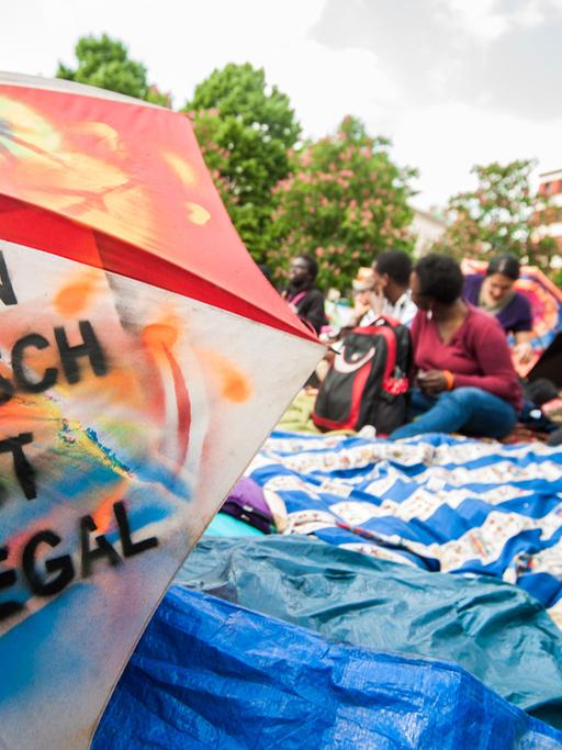 Ein Regenschirm mit der Aufschrift "Kein Mensch ist illegal" liegt am 30.04.2014 bei einer Pressekonferenz auf dem Oranienplatz in Berlin. Die Flüchtlinge und Aktivisten auf dem Berliner Oranienplatz haben ihren Hungerstreik nach einem Gespräch mit der Bundesbeauftragten für Flüchtlinge, Özugus, unterbrochen.