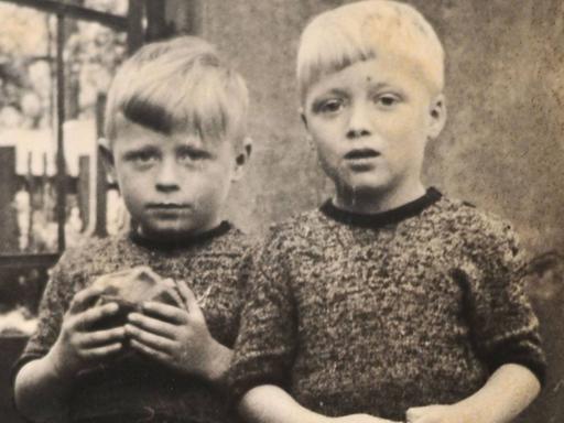 Eine alte Fotografie zweier Kinder. Eines hält einen Ball in der Hand.
