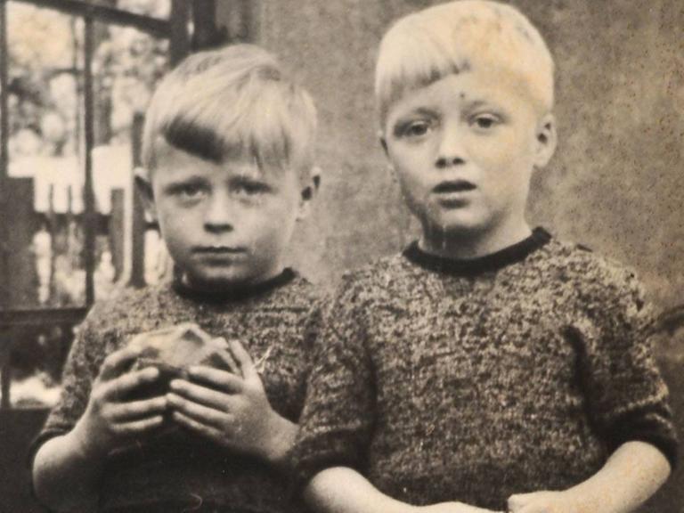 Eine alte Fotografie zweier Kinder. Eines hält einen Ball in der Hand.