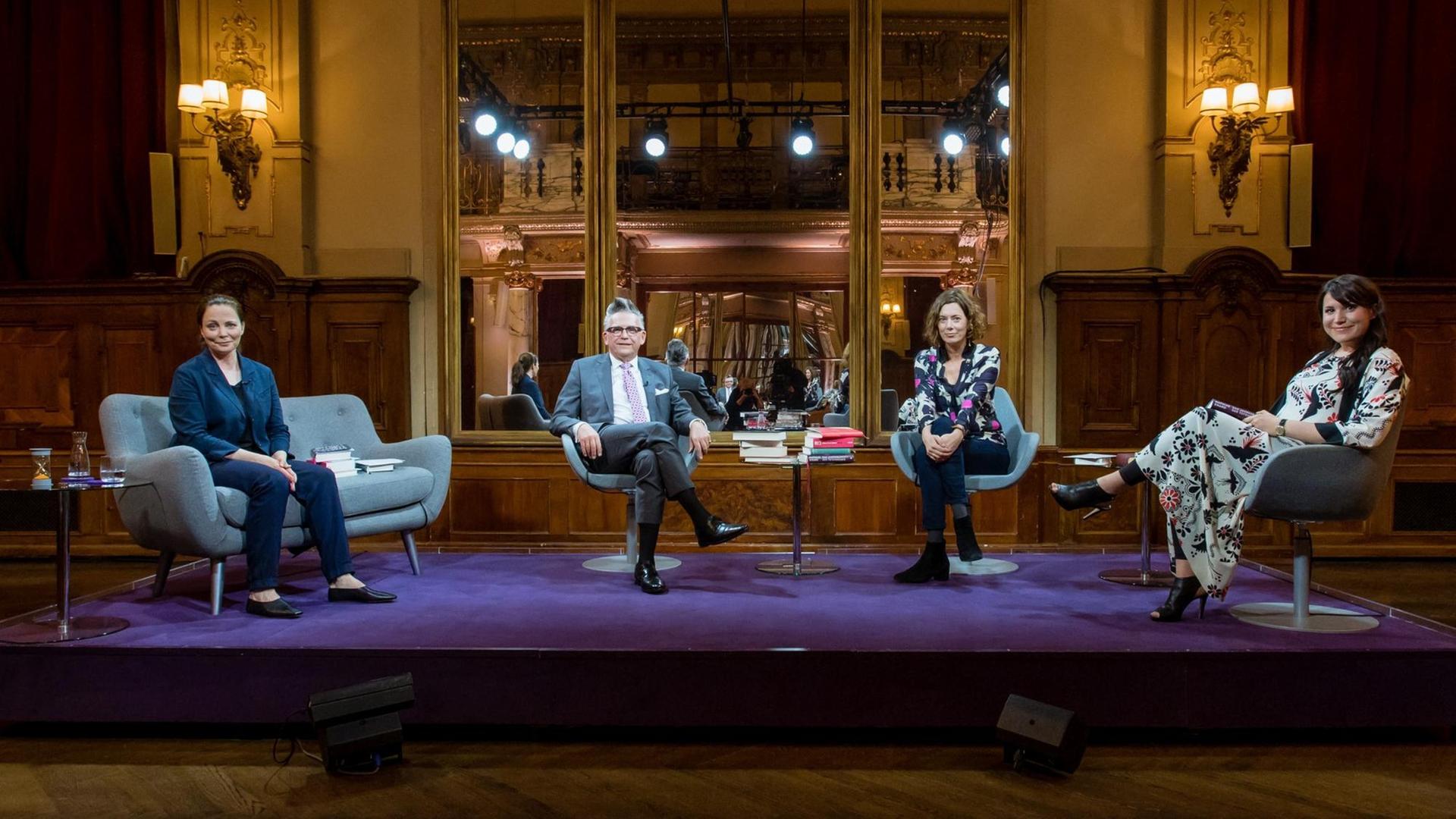 "Das Literarische Quartett": Thea Dorn, Götz Alsmann, Eva Menasse und Vea Kaiser sitzen, jeder auf seinem Stuhl oder kleinen Sofa, nebeneinander und schauen in die Kamera.