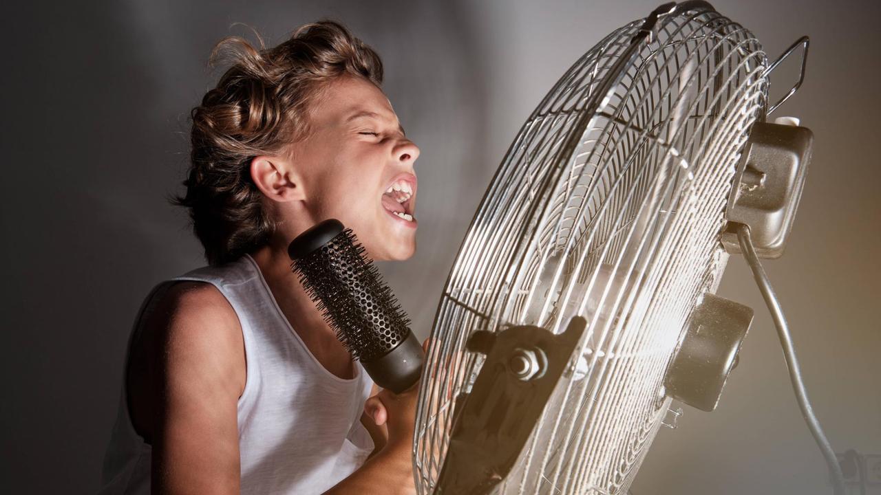 Ein Junge singt vor einem Ventilator in ein Haarbürsten-Mikrofon