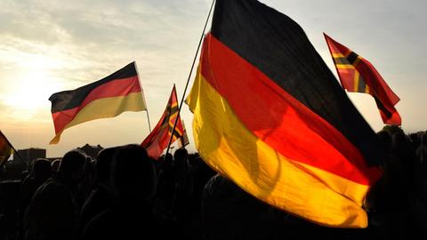 Deutschlandflaggen auf einer Demonstration neben Flaggen der rechten Reichsbürgerbewegung.