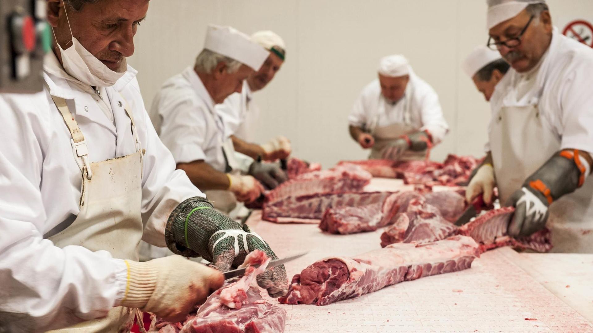 Arbeiter verarbeiten Fleisch in einem Schlachtbetrieb.