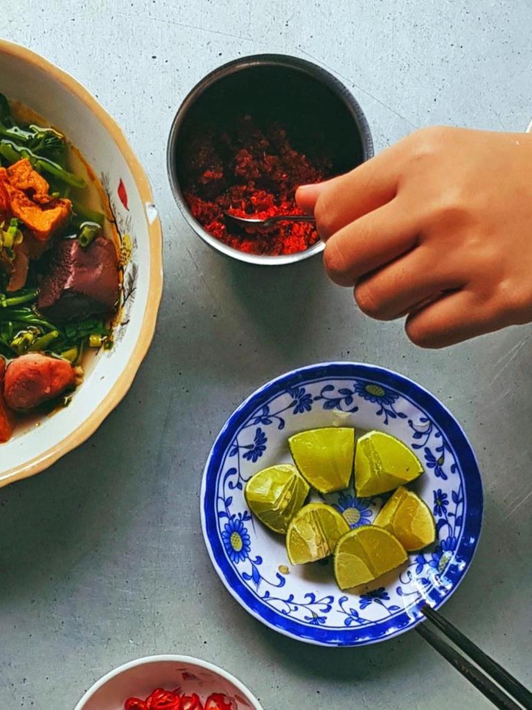 Draufsicht auf verschiedene Schalen mit asiatischem Essen, dazu eine Hand die nach Essen greift.