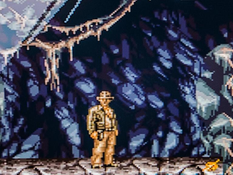 Screenshot des Computerspielklassikers "Indiana Jones' Greatest Adventures". Das stark verpixelte Bild zeigt Indiana Jones in einer Höhle.