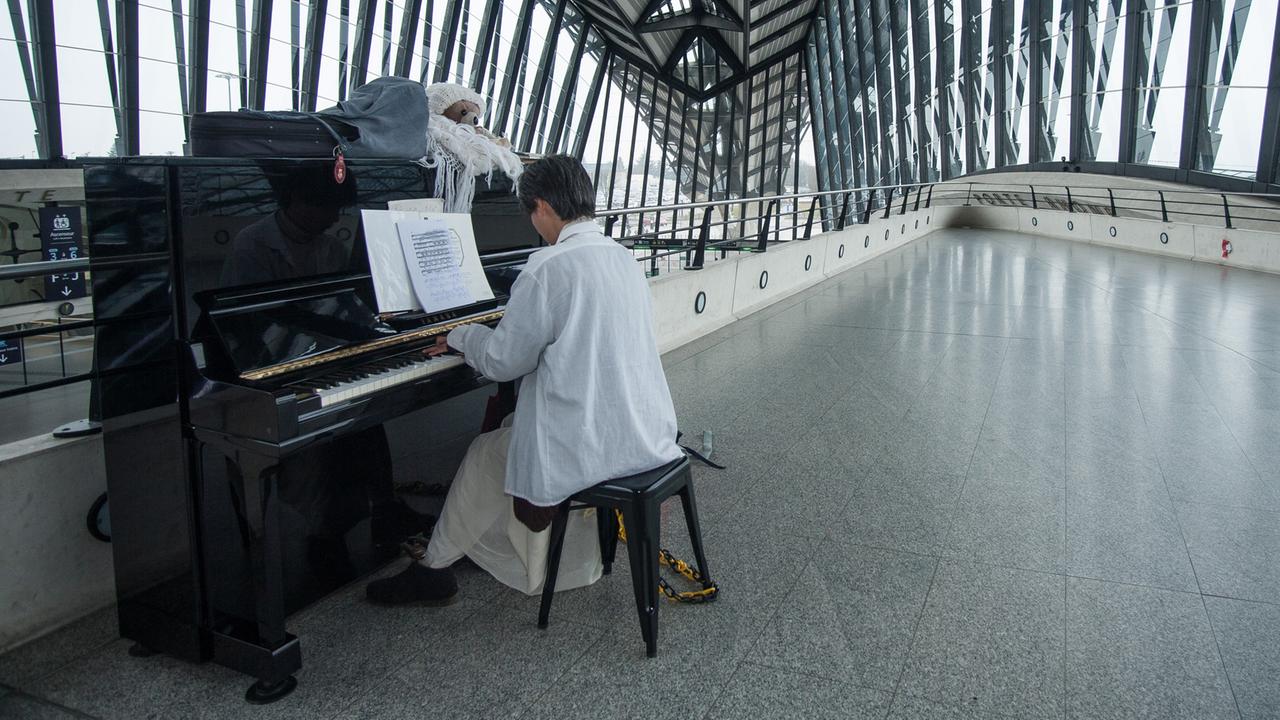 Eine Künstlerin spielt an einem öffentlichen Klavier im Flughafen Lyon - die Künstlerin lebt dort